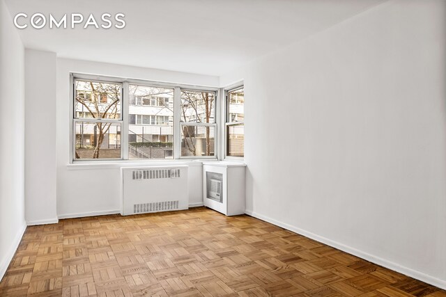 233 E 69th St Unit 2C, New York City, NY 10021 - empty room featuring radiator heating unit, baseboards, and healthy amount of natural light