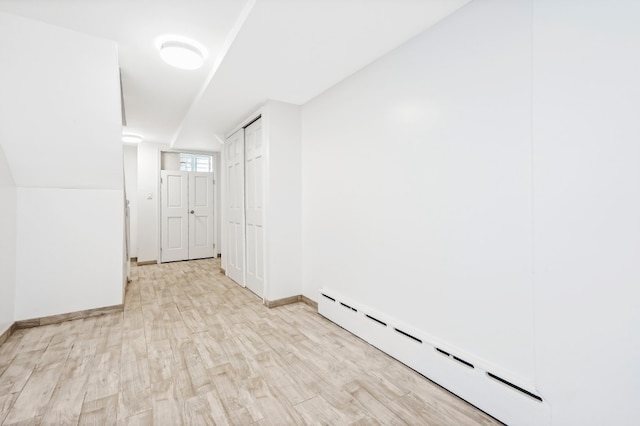 309 Covert St, New York City, NY 11237 - empty room with a baseboard heating unit, light wood-style floors, and baseboards