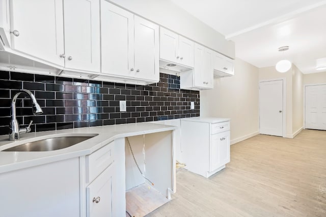 309 Covert St, New York City, NY 11237 - kitchen with a sink, light wood-type flooring, white cabinetry, and decorative backsplash