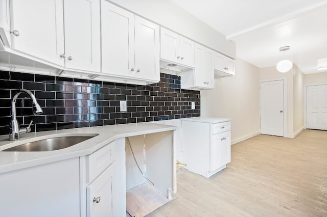 309 Covert St, New York City, NY 11237 - kitchen with a sink, light wood-type flooring, white cabinets, and decorative backsplash