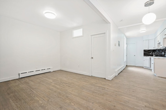 309 Covert St, New York City, NY 11237 - unfurnished room featuring a baseboard heating unit, light wood-style floors, a sink, and baseboards