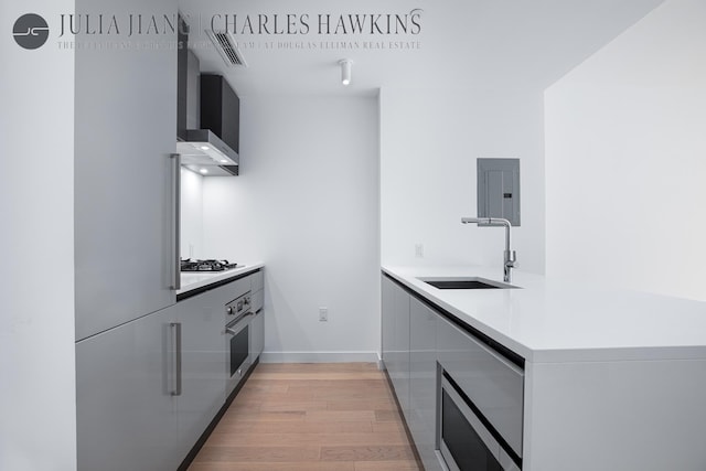 540 W 49th St Unit 307S, New York City, NY 10019 - kitchen featuring modern cabinets, wall chimney range hood, electric panel, stainless steel appliances, and light wood-type flooring
