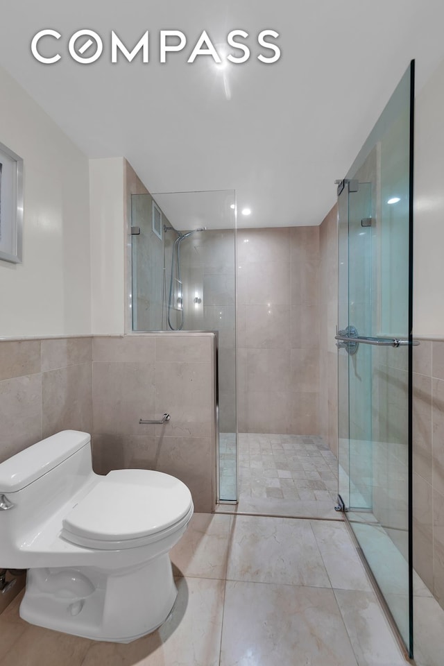full bath with tile walls, a shower stall, and toilet