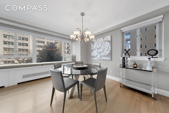 dining room with baseboards, ornamental molding, wood finished floors, and a chandelier