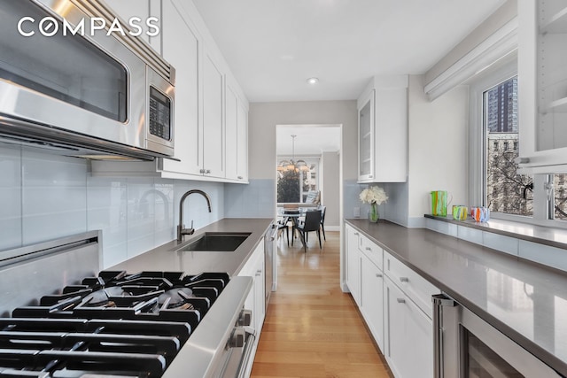 200 E 66th St Unit A407, New York City, NY 10065 - kitchen with stainless steel microwave, wine cooler, a sink, light wood-type flooring, and white cabinets