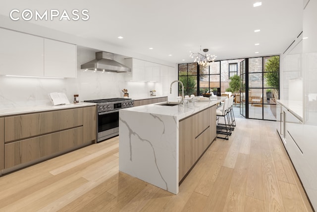 54 E 80th St, New York City, NY 10075 - kitchen featuring modern cabinets, wall chimney range hood, high end stove, a sink, and a wall of windows