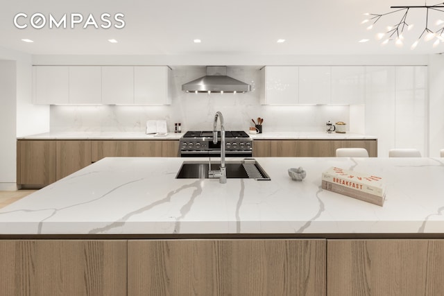 54 E 80th St, New York City, NY 10075 - kitchen with modern cabinets, wall chimney exhaust hood, light stone countertops, backsplash, and gas range