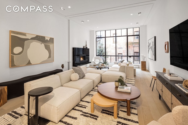 54 E 80th St, New York City, NY 10075 - living area with floor to ceiling windows, light wood finished floors, recessed lighting, and a warm lit fireplace