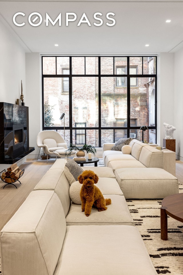 54 E 80th St, New York City, NY 10075 - living area featuring a wall of windows, a lit fireplace, plenty of natural light, recessed lighting, and wood finished floors