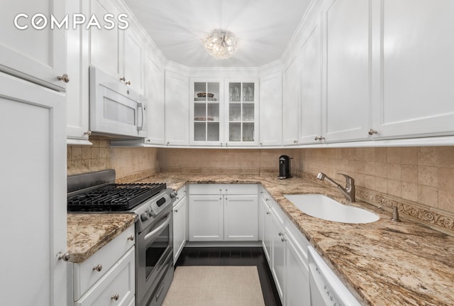 kitchen featuring a sink, white microwave, white cabinetry, and gas stove