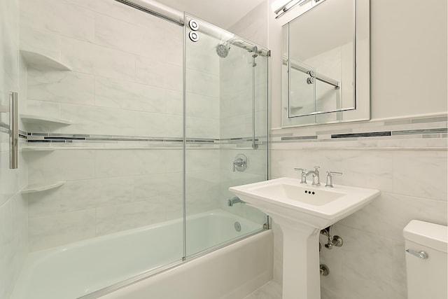 bathroom with toilet, enclosed tub / shower combo, and tile walls