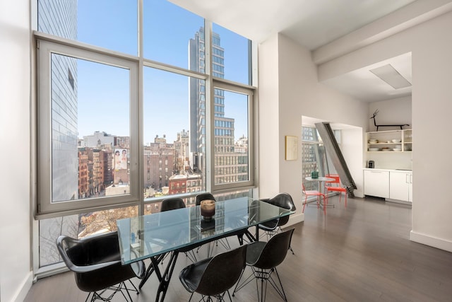 dining room featuring baseboards, wood finished floors, a city view, and a towering ceiling