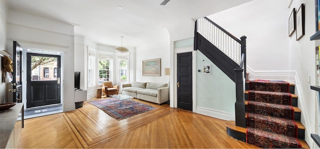 living room featuring wood finished floors, baseboards, and stairs