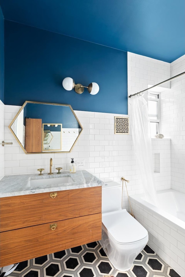bathroom featuring tiled shower / bath, vanity, toilet, and tile walls
