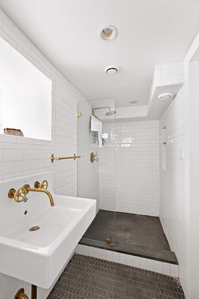 bathroom with a stall shower, tile patterned flooring, a sink, and tile walls
