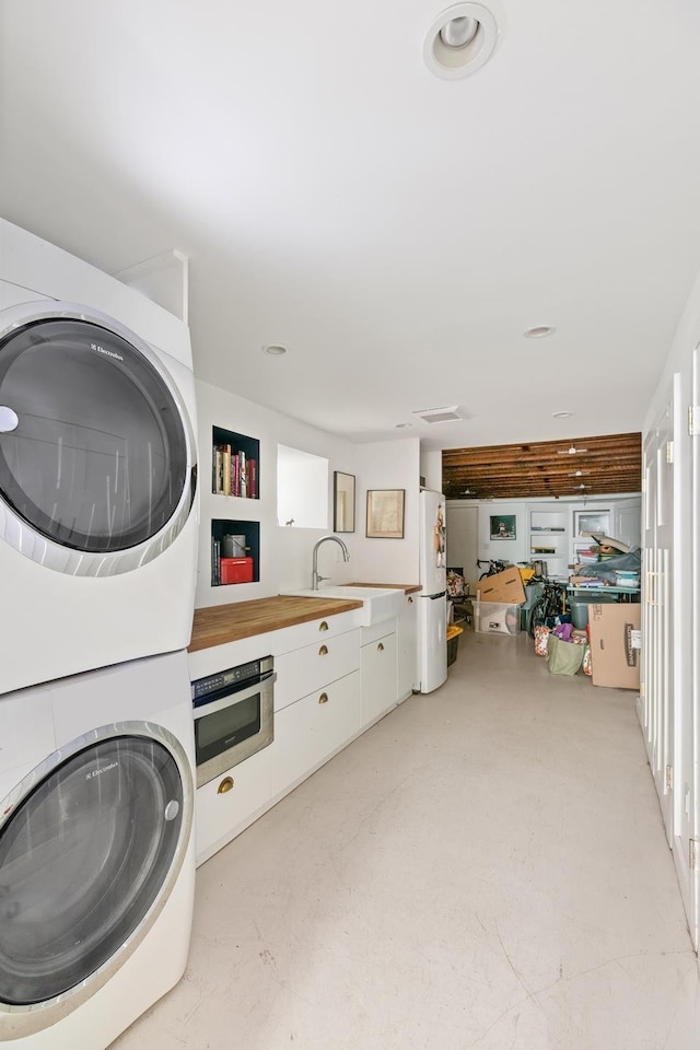 laundry area featuring a sink, stacked washing maching and dryer, and laundry area
