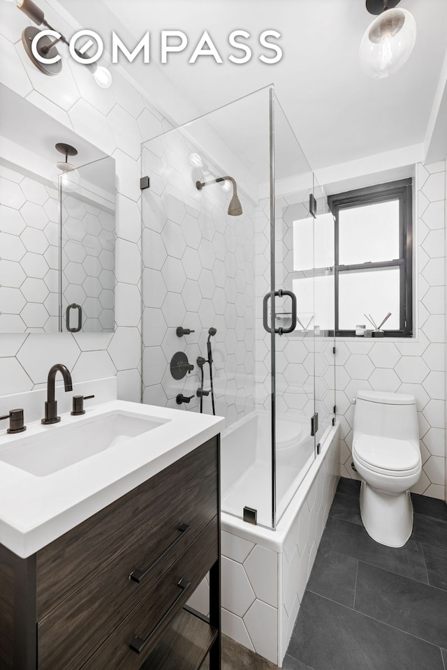 235 E 22nd St Unit 4T, New York City, NY 10010 - full bathroom with tile walls, combined bath / shower with glass door, toilet, vanity, and tile patterned flooring