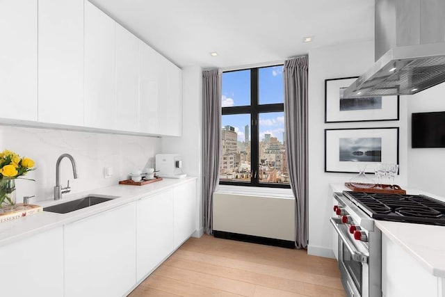 kitchen featuring wall chimney exhaust hood, high end stainless steel range, a sink, and modern cabinets
