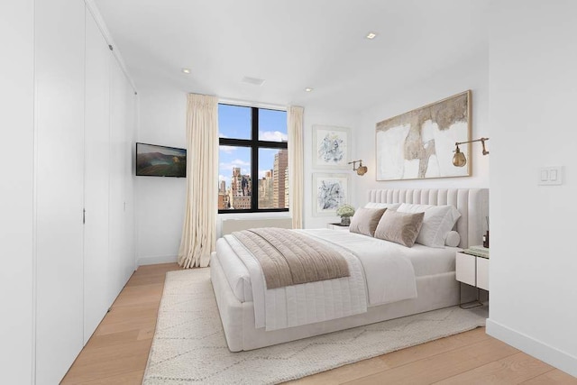 bedroom with light wood-type flooring, baseboards, and recessed lighting