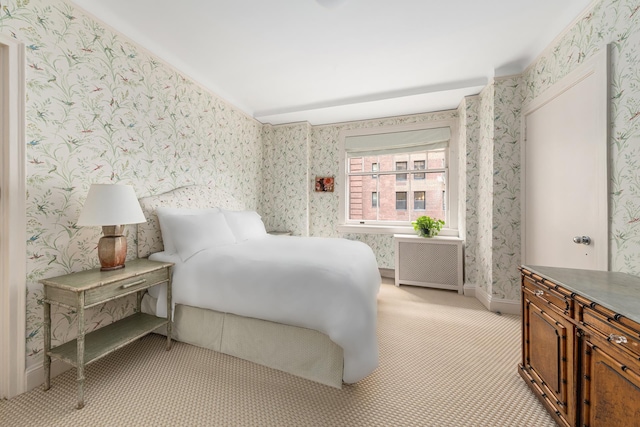 bedroom with wallpapered walls, radiator heating unit, and light carpet
