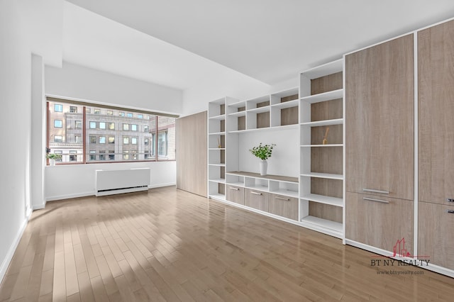 350 W 50th St Unit 6-R, New York City, NY 10019 - unfurnished living room with wood finished floors, radiator, and baseboards