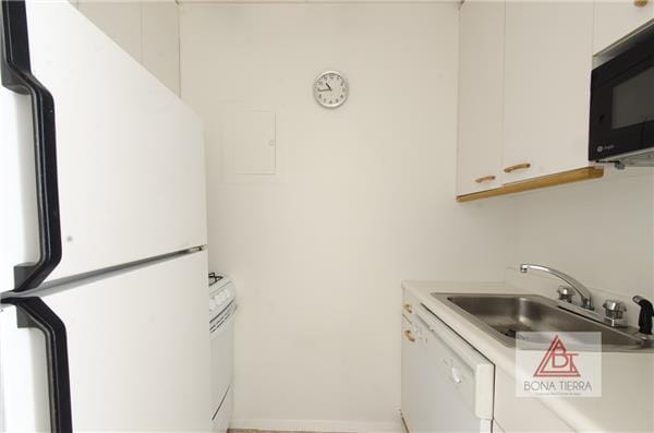 350 W 50th St Unit 6-R, New York City, NY 10019 - kitchen featuring white appliances, a sink, light countertops, and white cabinetry