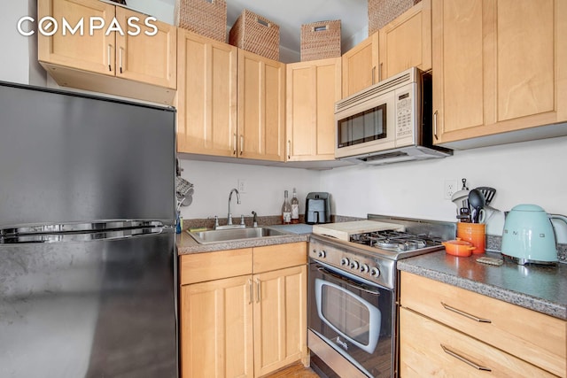 352 W 12th St Unit 5D, New York City, NY 10014 - kitchen featuring freestanding refrigerator, white microwave, light brown cabinets, stainless steel range with gas stovetop, and a sink