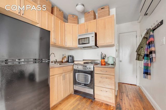 352 W 12th St Unit 5D, New York City, NY 10014 - kitchen featuring freestanding refrigerator, white microwave, stainless steel range with gas stovetop, light brown cabinetry, and a sink
