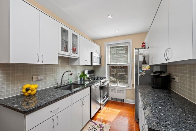 9437 Shore Rd Unit A1, New York City, NY 11209 - kitchen featuring a sink, radiator heating unit, appliances with stainless steel finishes, decorative backsplash, and white cabinets