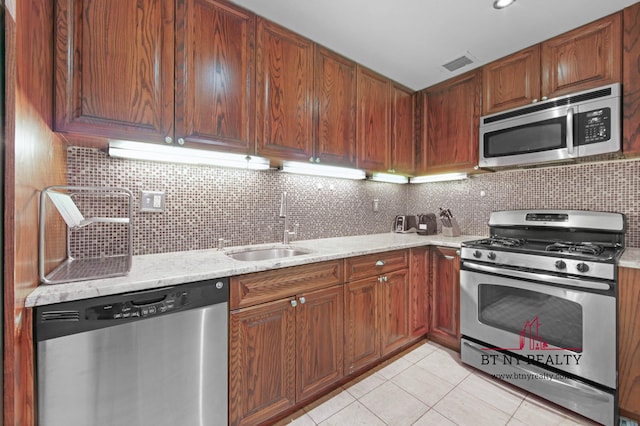 216 E 47th St Unit 4-A, New York City, NY 10017 - kitchen featuring stainless steel appliances, light tile patterned flooring, a sink, decorative backsplash, and brown cabinetry