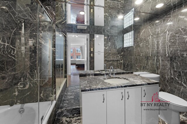 216 E 47th St Unit 4-A, New York City, NY 10017 - ensuite bathroom with tile walls, vanity, toilet, marble tiled floors, and shower / tub combination