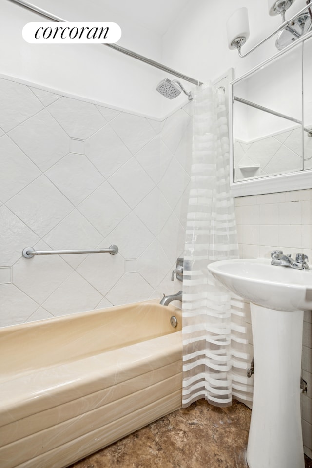bathroom featuring tile walls, shower / tub combo with curtain, and a sink