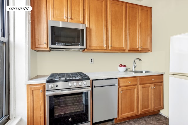 kitchen with stainless steel appliances, a sink, light countertops, and brown cabinets