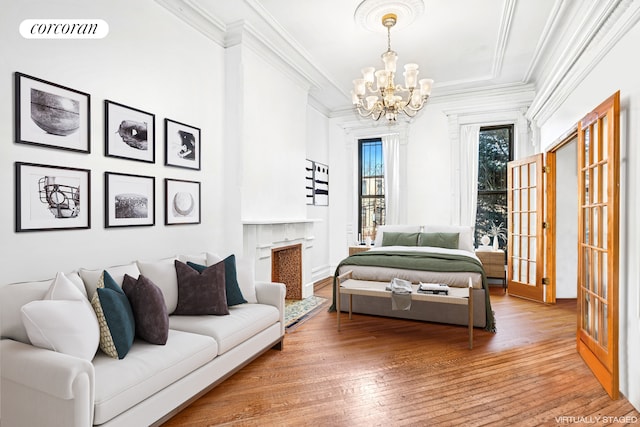 living area featuring crown molding, a chandelier, hardwood / wood-style floors, and french doors