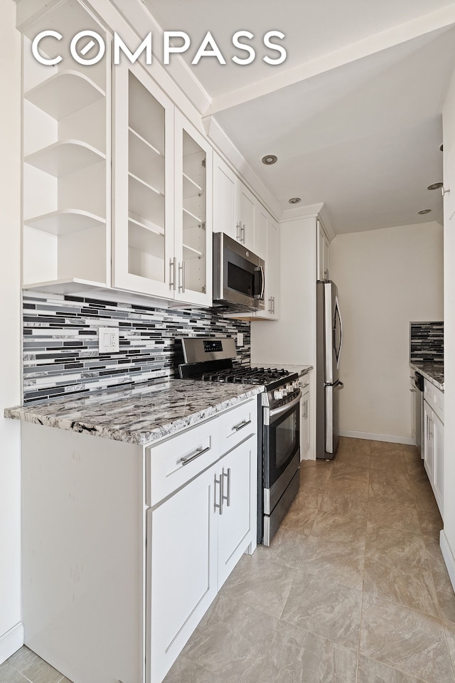 kitchen featuring light stone countertops, glass insert cabinets, stainless steel appliances, backsplash, and white cabinetry