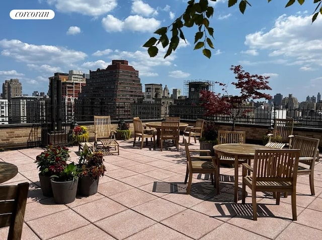 view of patio featuring a skyline view, outdoor dining area, and fence