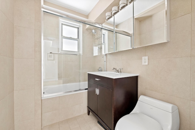 bathroom featuring tile walls, tiled shower / bath, toilet, vanity, and tile patterned flooring