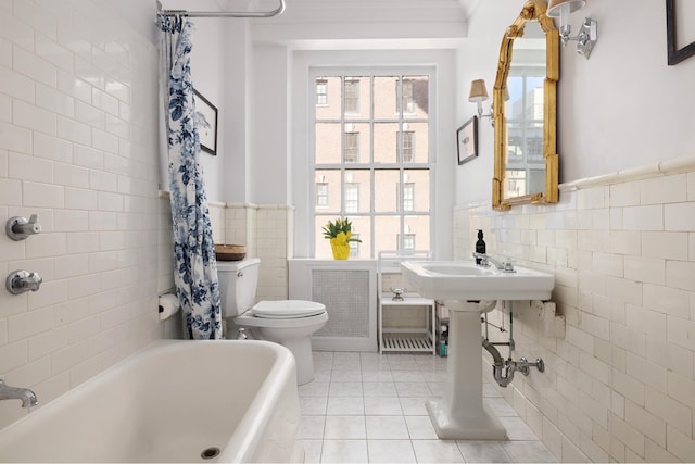 bathroom featuring tile patterned floors, tile walls, a wainscoted wall, radiator, and toilet