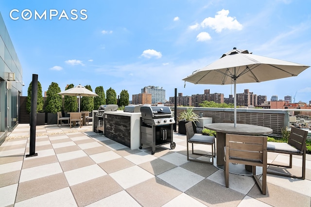 view of patio / terrace featuring a skyline view, outdoor dining area, area for grilling, and an outdoor kitchen