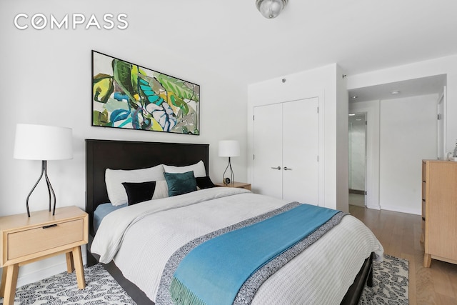 bedroom with wood finished floors, a closet, and baseboards
