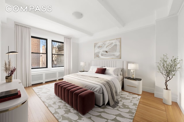 bedroom featuring light wood-style flooring and beamed ceiling