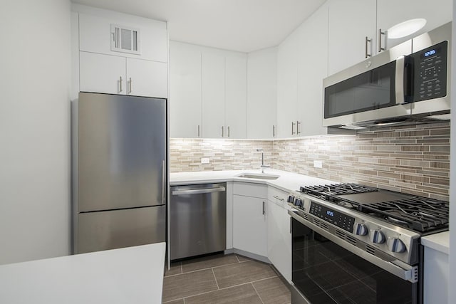 300 E 40th St Unit 23-G, New York City, NY 10016 - kitchen with appliances with stainless steel finishes, a sink, light countertops, white cabinetry, and backsplash