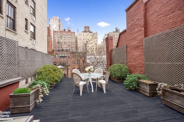 wooden terrace featuring a city view and outdoor dining area