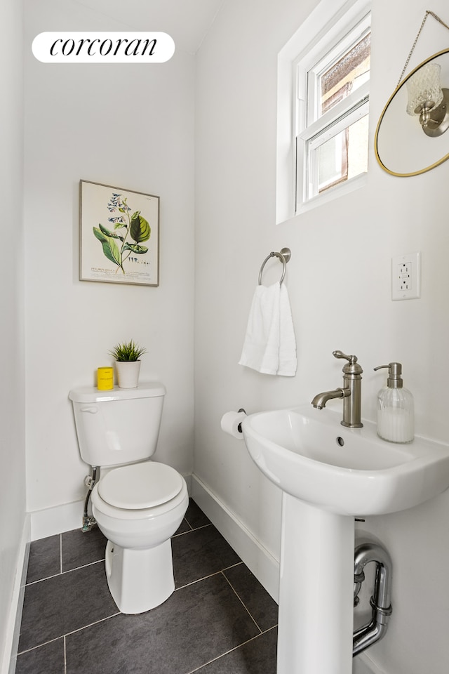 half bathroom featuring toilet, tile patterned floors, and baseboards