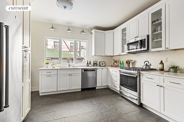 kitchen with white cabinets, stainless steel appliances, a sink, and light countertops