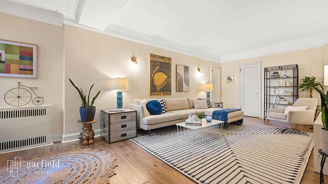 living area with crown molding, baseboards, heating unit, and wood finished floors