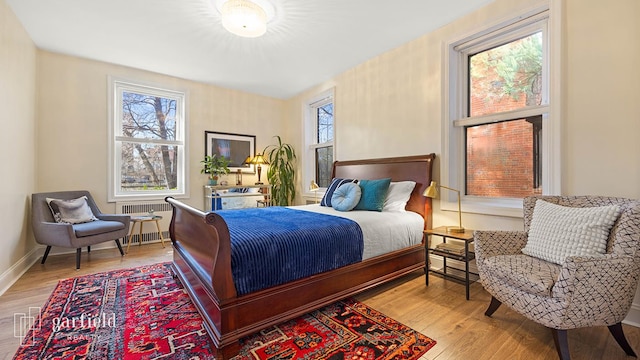 bedroom featuring baseboards, wood finished floors, and radiator
