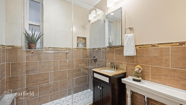full bathroom with vanity, a shower stall, and tile walls