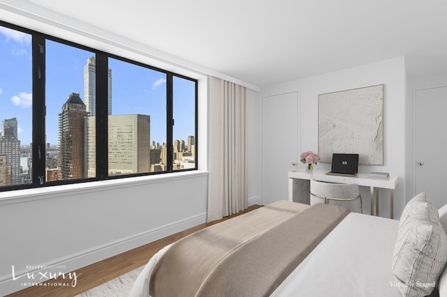 30 W 61st St Unit 24C, New York City, NY 10023 - bedroom featuring baseboards, a view of city, and wood finished floors