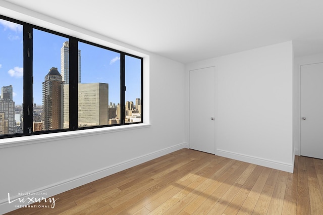 30 W 61st St Unit 24C, New York City, NY 10023 - spare room featuring hardwood / wood-style flooring, a city view, and baseboards
